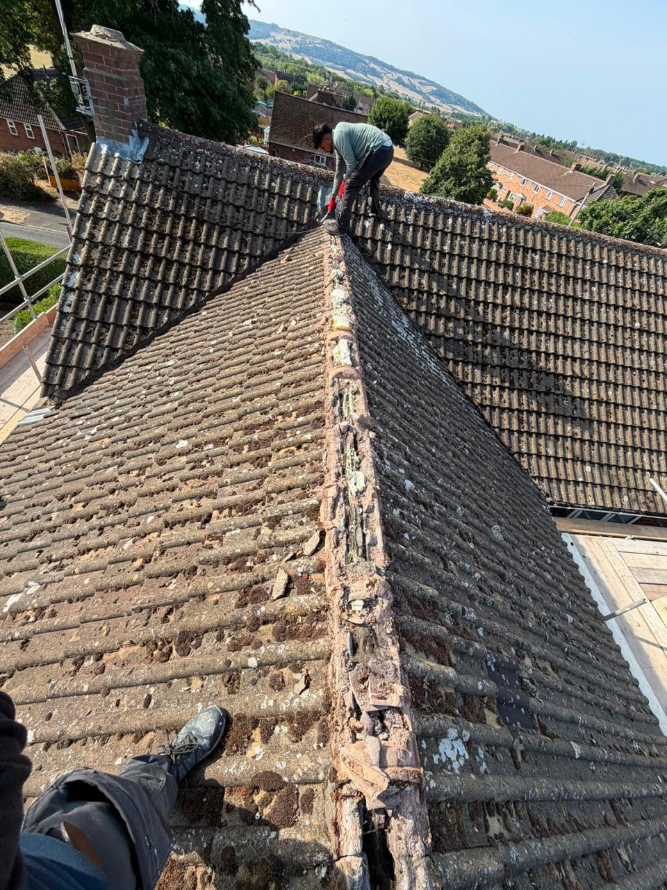 Before roof repair showing old ridge tiles and weathered roof covering
